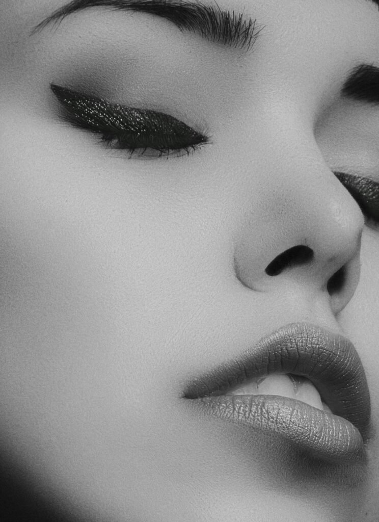 Artistic black and white close-up portrait of a woman's face with glamorous makeup.